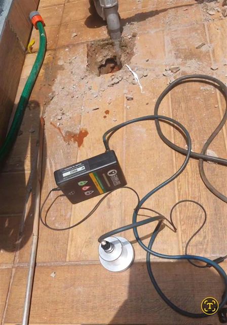 Geofone posicionado no piso para localizar um vazamento, com abertura feita só no ponto do conserto