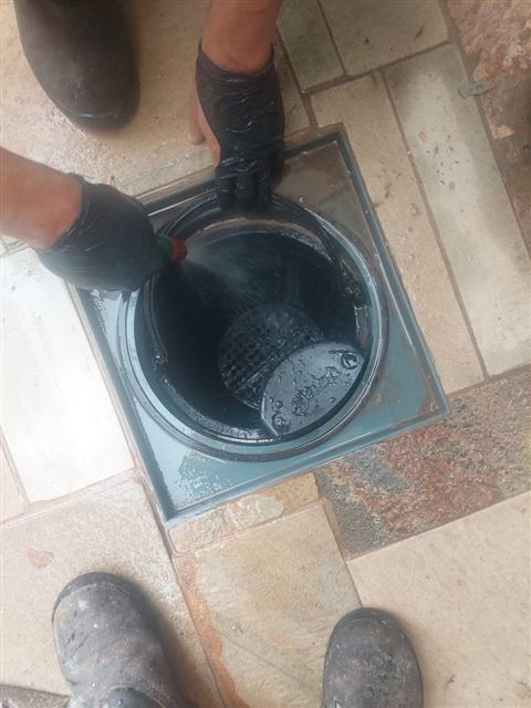 Técnico de luvas limpando uma caixa no piso
