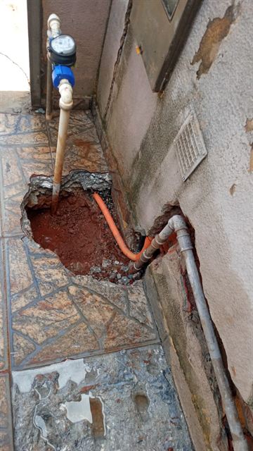 Piso aberto junto ao hidrômetro para consertar um vazamento na entrada de água