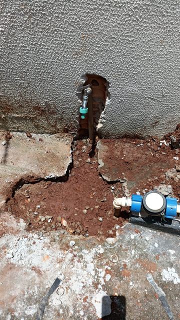Vala aberta entre o hidrômetro e a torneira do quintal para refazer a tubulação