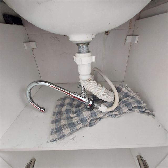 Sifão e torneira instalados embaixo de uma pia
